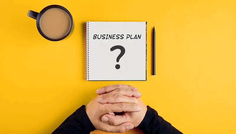 Folded hands with a business plan and a question mark